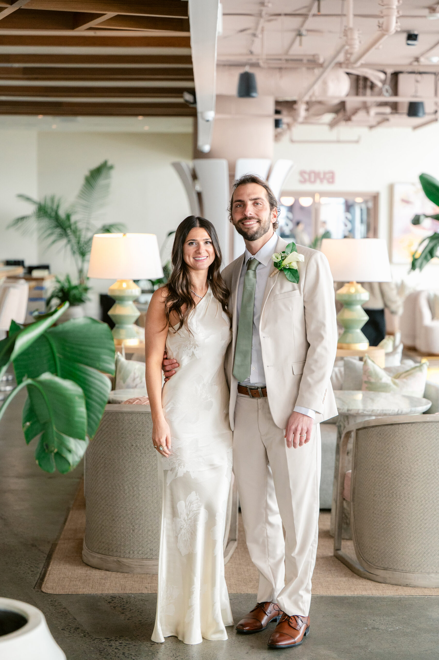 Bride and groom smiling together inside Wave Resort in Long Branch, NJ during their winter wedding, surrounded by soft coastal decor and greenery.
